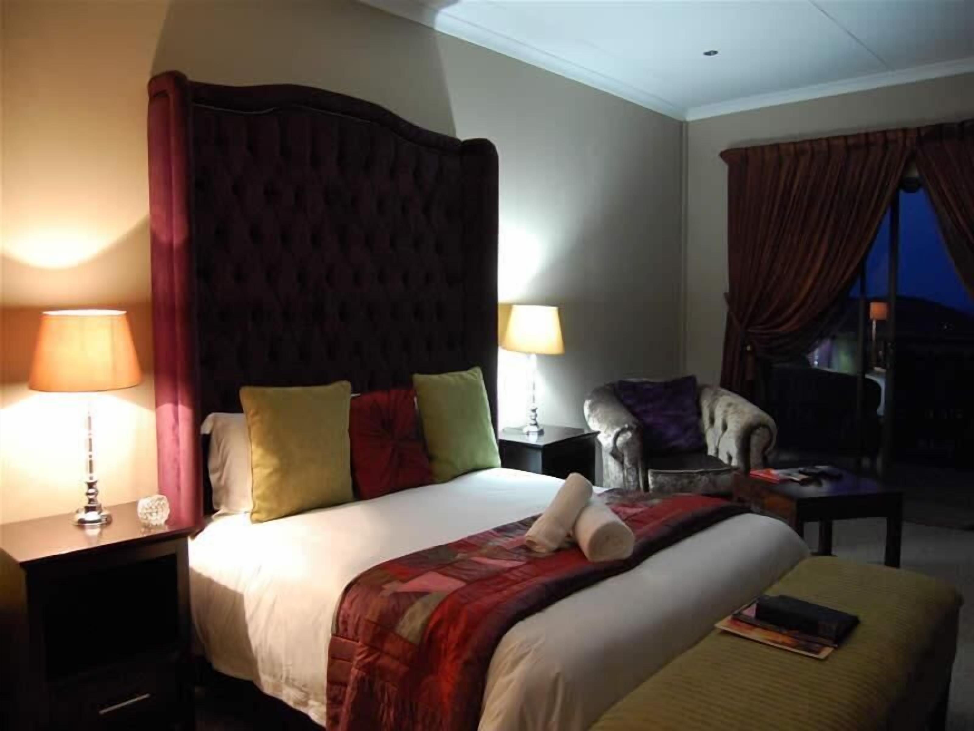 A hotel room with a large bed, two bedside tables with lamps, a chair, and a window with curtains.