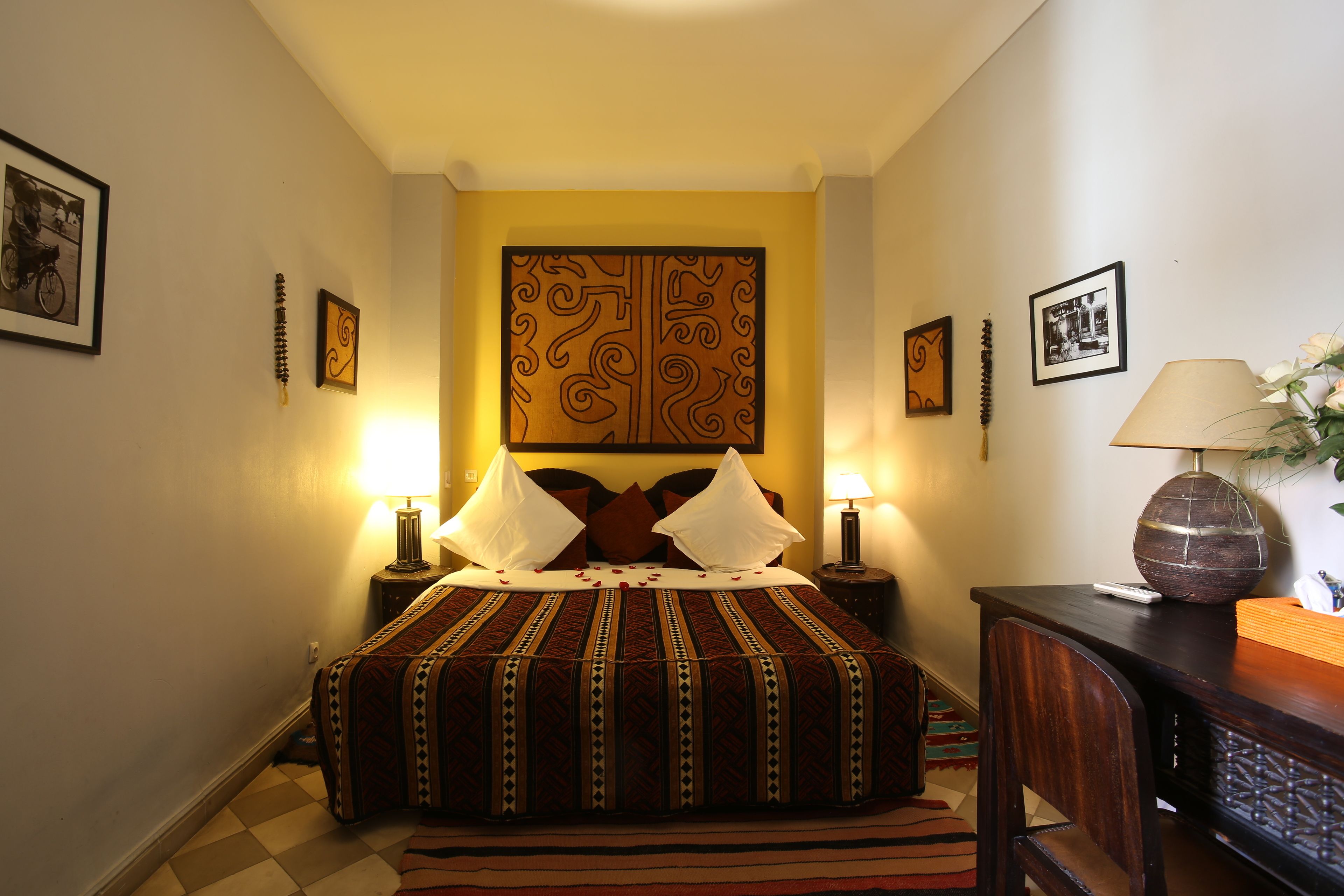 Quarto bem arrumado com uma cama grande, duas luminárias de cabeceira, um painel decorativo na cabeceira e uma pequena mesa com uma luminária.