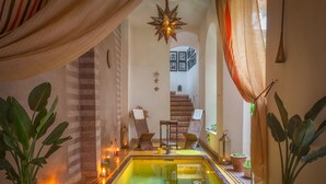 Un área de spa con una piscina pequeña, velas y plantas en macetas.