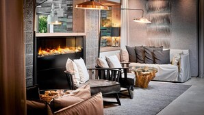 A cozy living room with a fireplace, modern furniture, and a stone wall. - Antonius (Kaprun)