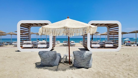 Een privéstrand, ligstoelen aan het strand, parasols, strandlakens. Evilion Sea And Sun