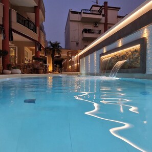 Una piscina al aire libre, sombrillas, sillones reclinables de piscina