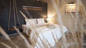 Un dormitorio con cama, una hamaca colgante, un cuadro en la pared y una estantería con objetos decorativos.