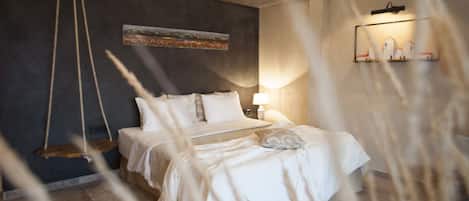 A bedroom with a bed, a hanging swing, a painting on the wall, and a shelf with decorative items.