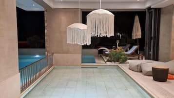 Una piscina al aire libre, sombrillas, sillones reclinables de piscina