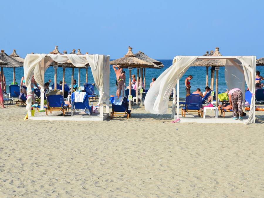Een privéstrand, ligstoelen aan het strand, parasols, strandlakens