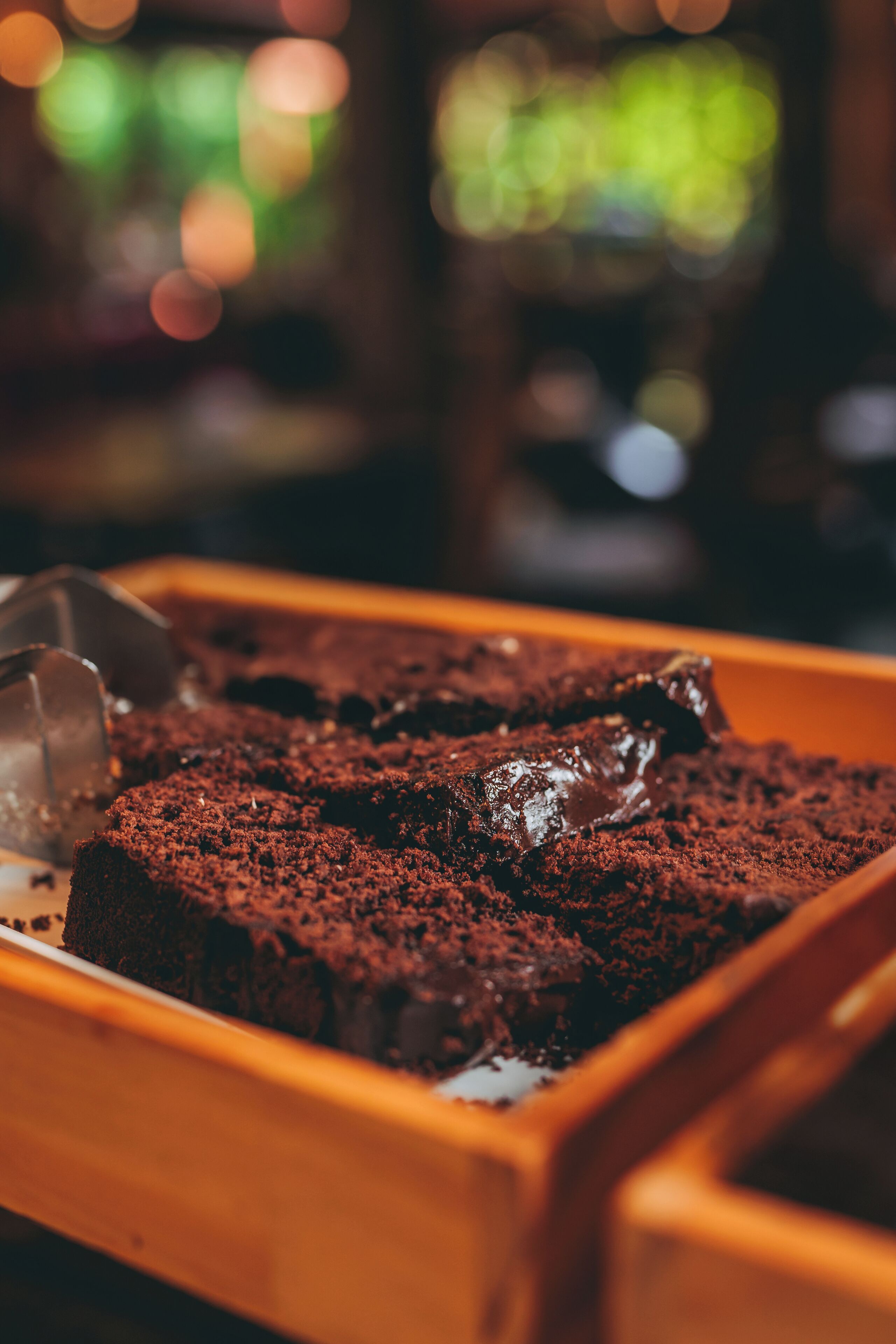 Un plateau de brownies recouverts d’un glaçage au chocolat, posé sur une surface en bois.