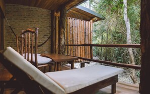 Une terrasse en bois avec un banc et une table, donnant sur une zone boisée.