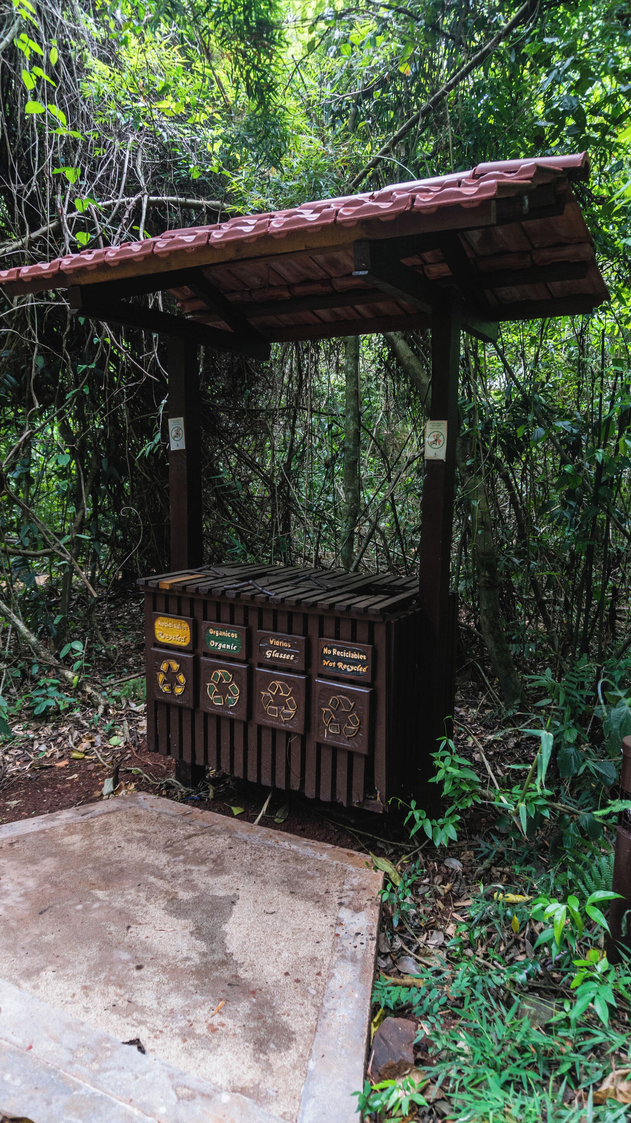 A wooden structure with a roof, possibly a shelter, surrounded by dense greenery.
