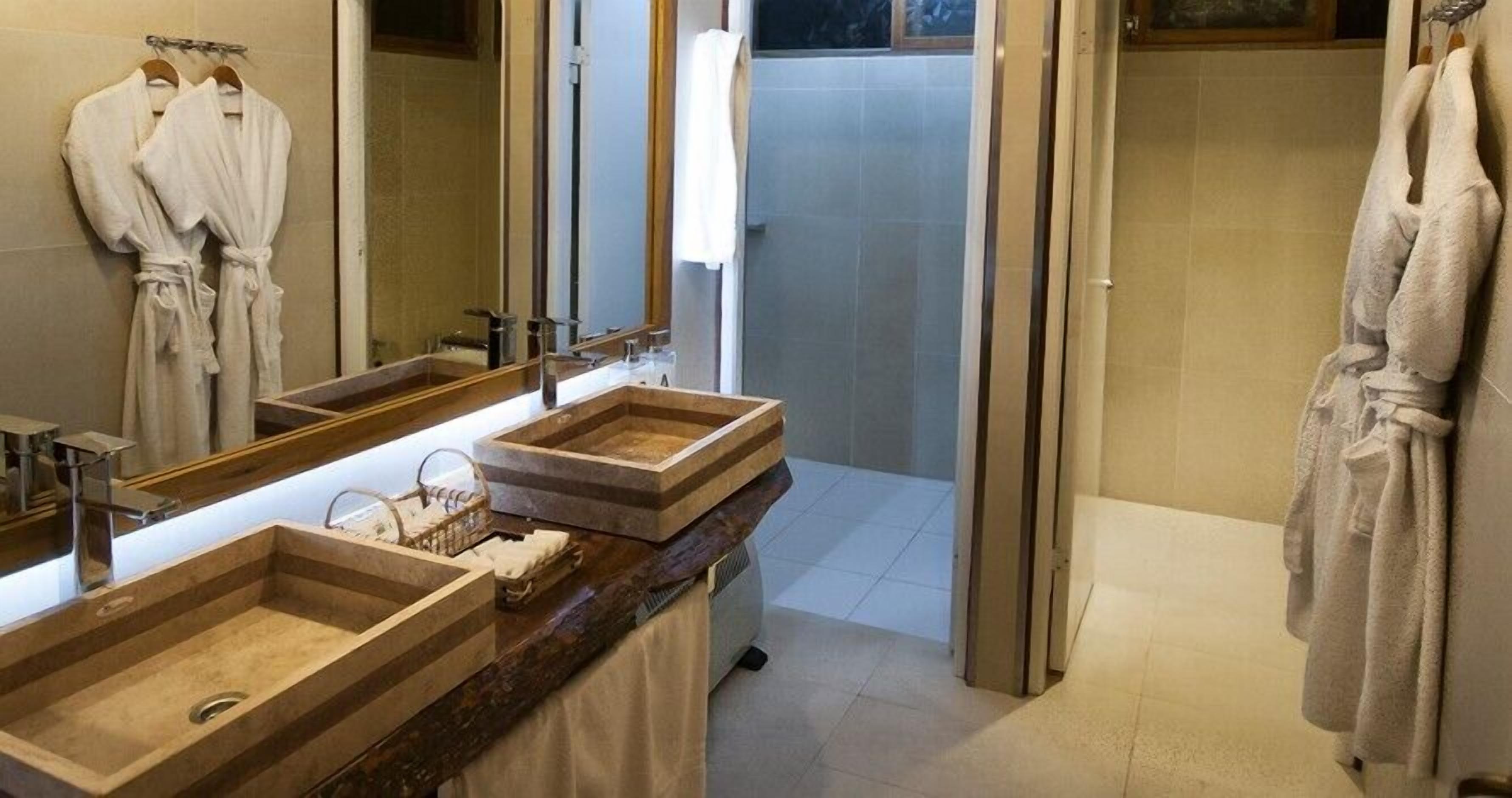 A bathroom with two sinks, a mirror, and a shower area.