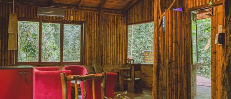Un intérieur en bois avec des murs en bambou, des sièges rouges et de grandes fenêtres.