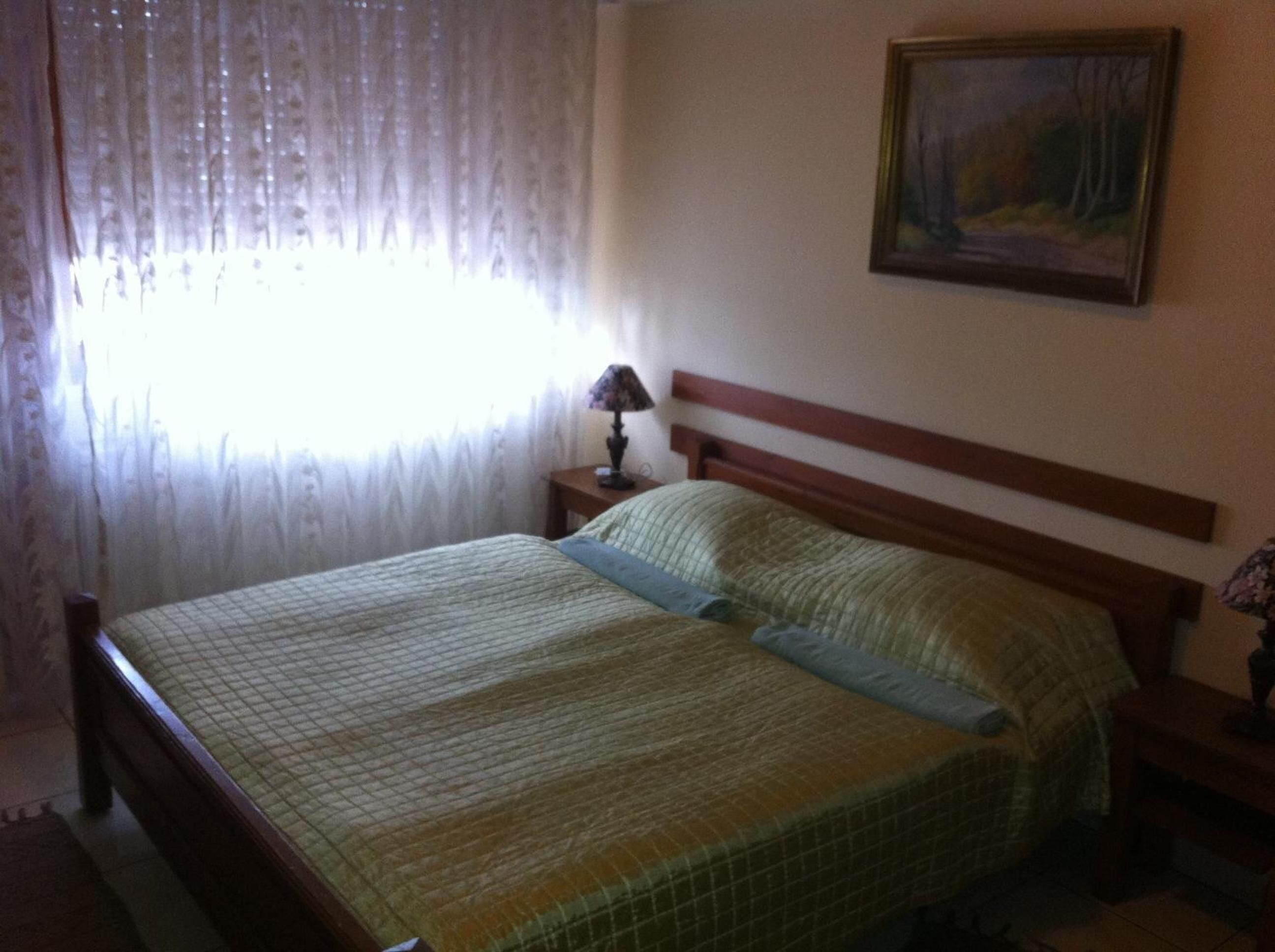 Un dormitorio con una cama, una mesita de noche, una lámpara y un cuadro en la pared.