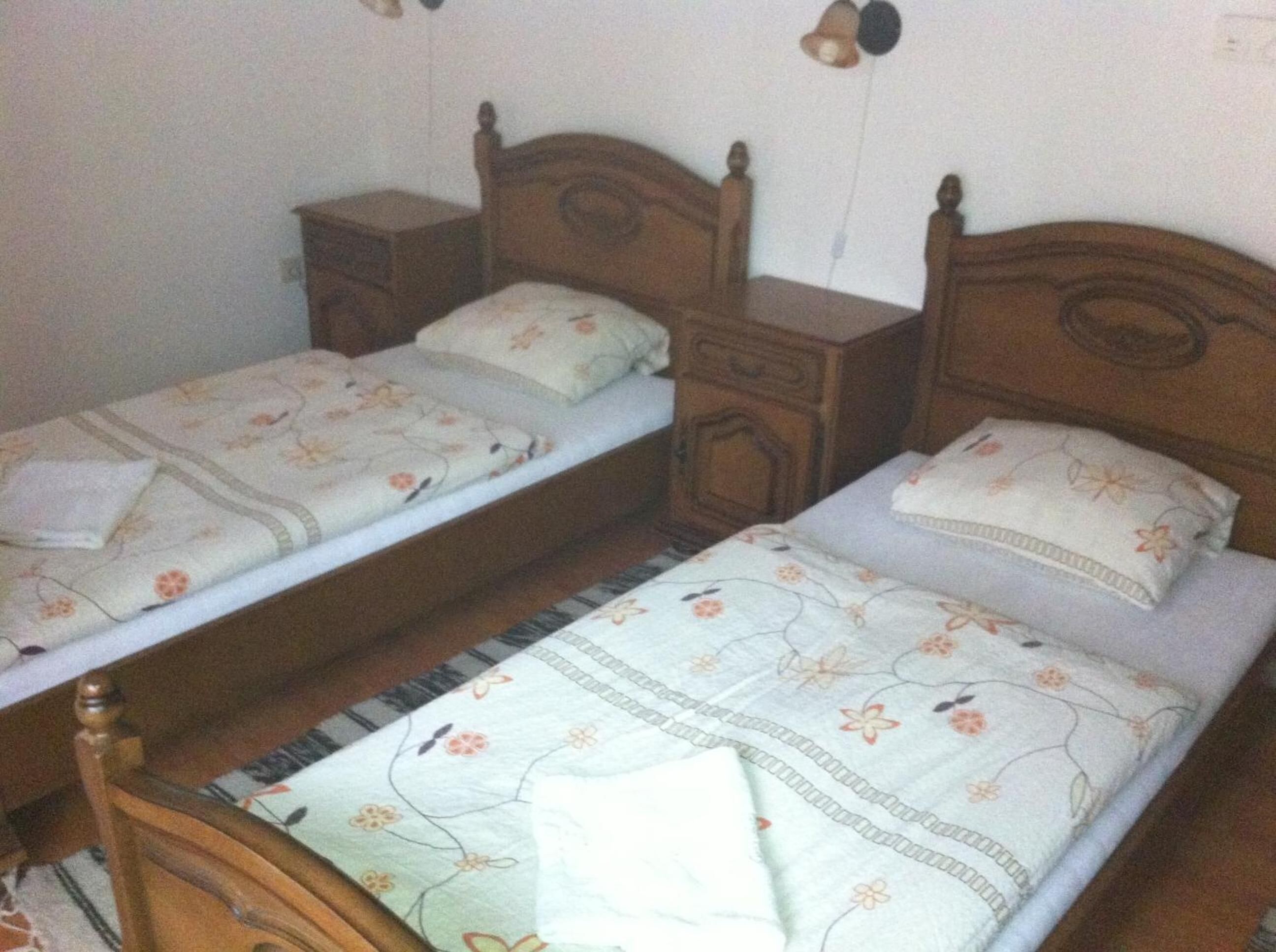 A bedroom with two single beds, wooden headboards, and matching nightstands.