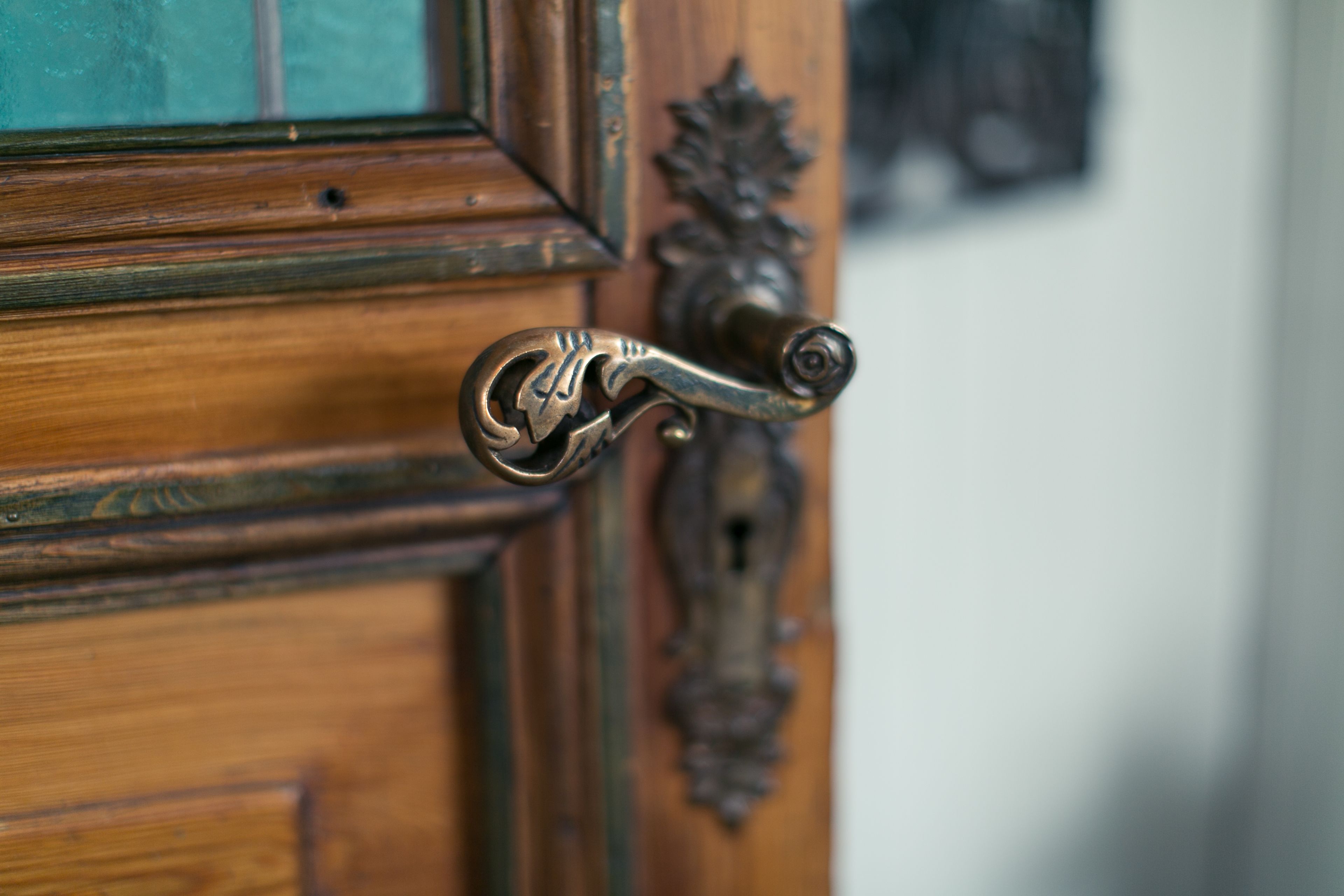 A wooden door with a brass, ornate handle.