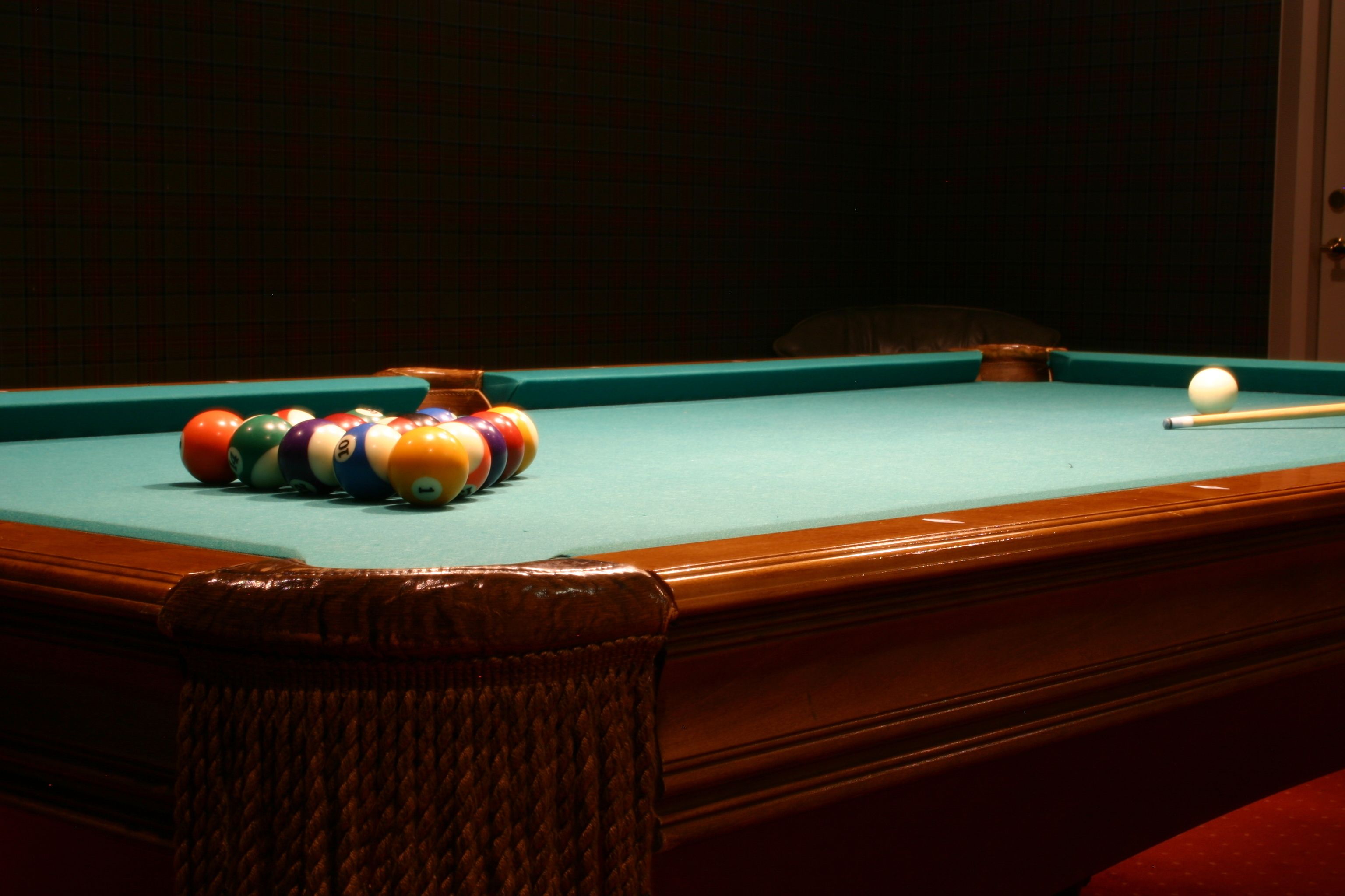 A pool table with balls and a cue stick.