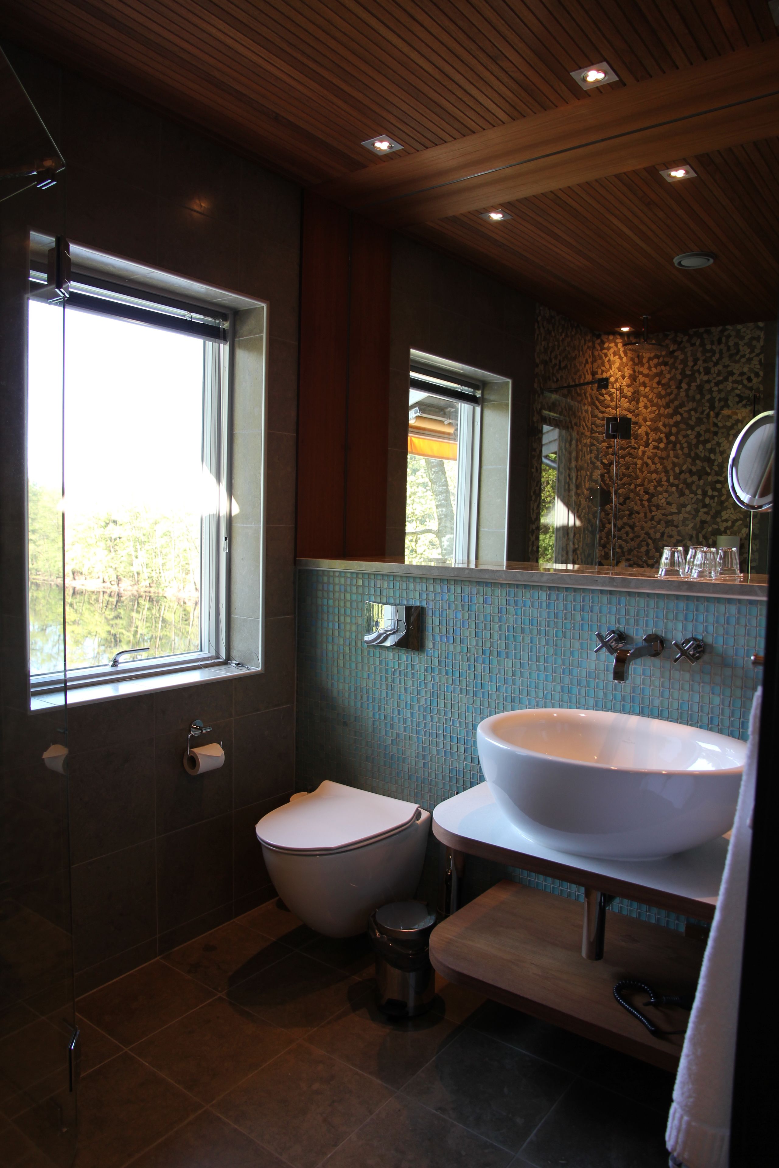 Ein modernes Badezimmer mit Toilette, Bidet, Waschbecken und einem großen Spiegel.
