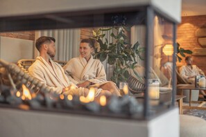 A couple in a cozy, well-lit room with a fireplace, comfortable seating, and a plant. - HESTRAVIKEN HOTEL & SPA (Hestra)