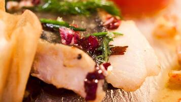 Une vue rapprochée d’un plat composé de poisson, de légumes verts et d’une tomate cerise.