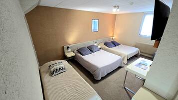 Een hotelkamer met twee bedden, een tafeltje, een stoel, een televisie en een raam.