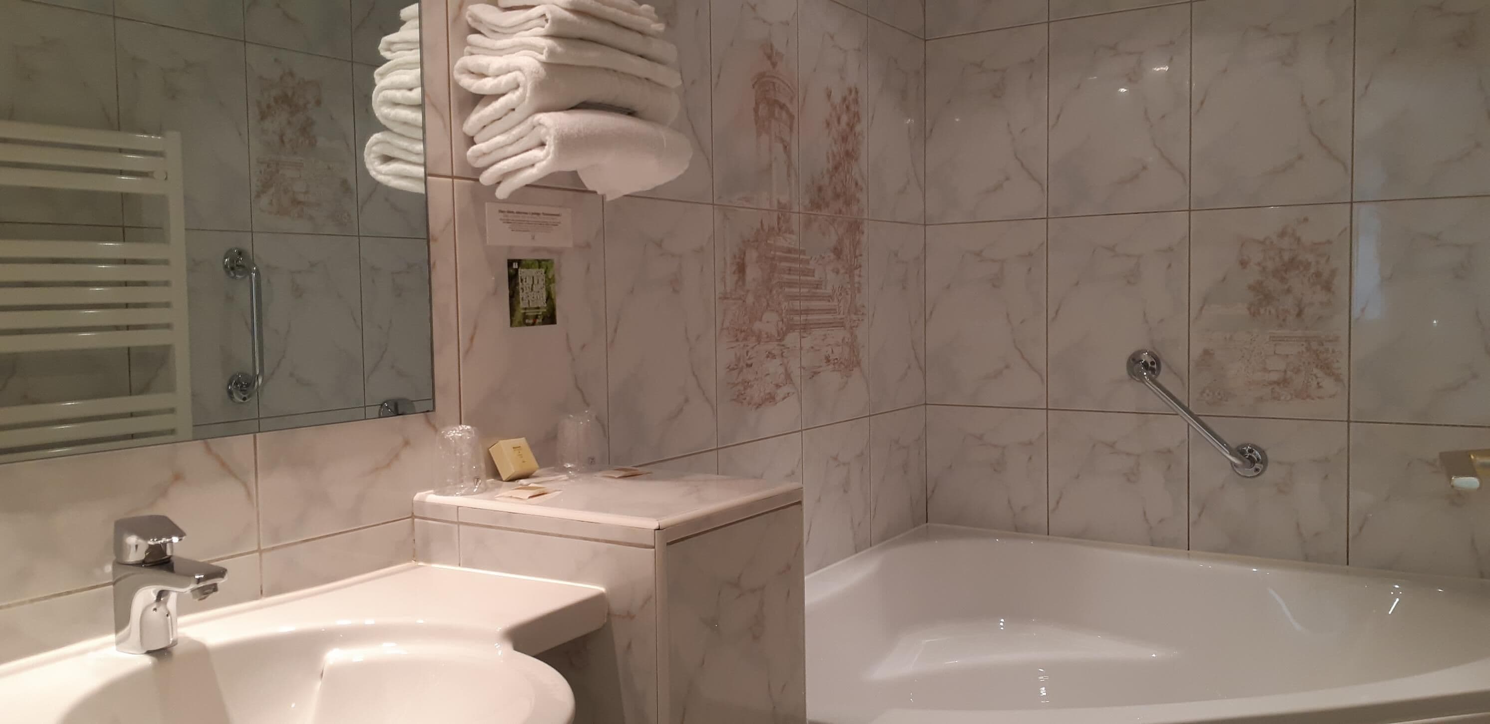 A bathroom with a bathtub, a sink, and a towel rack with folded towels.