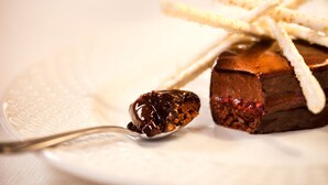 Un dessert con un cucchiaio di salsa al cioccolato su un piatto bianco.