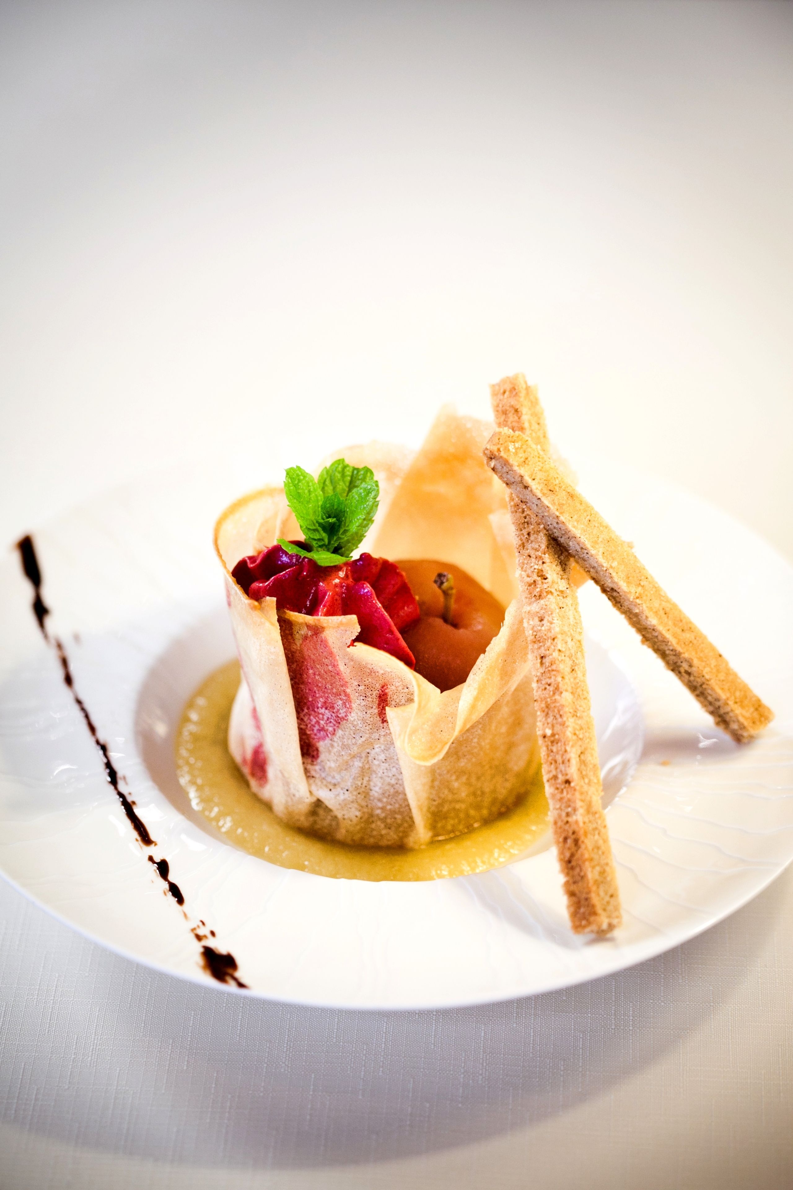 Un postre sobre un plat blanc amb un reguitzell de xocolata.