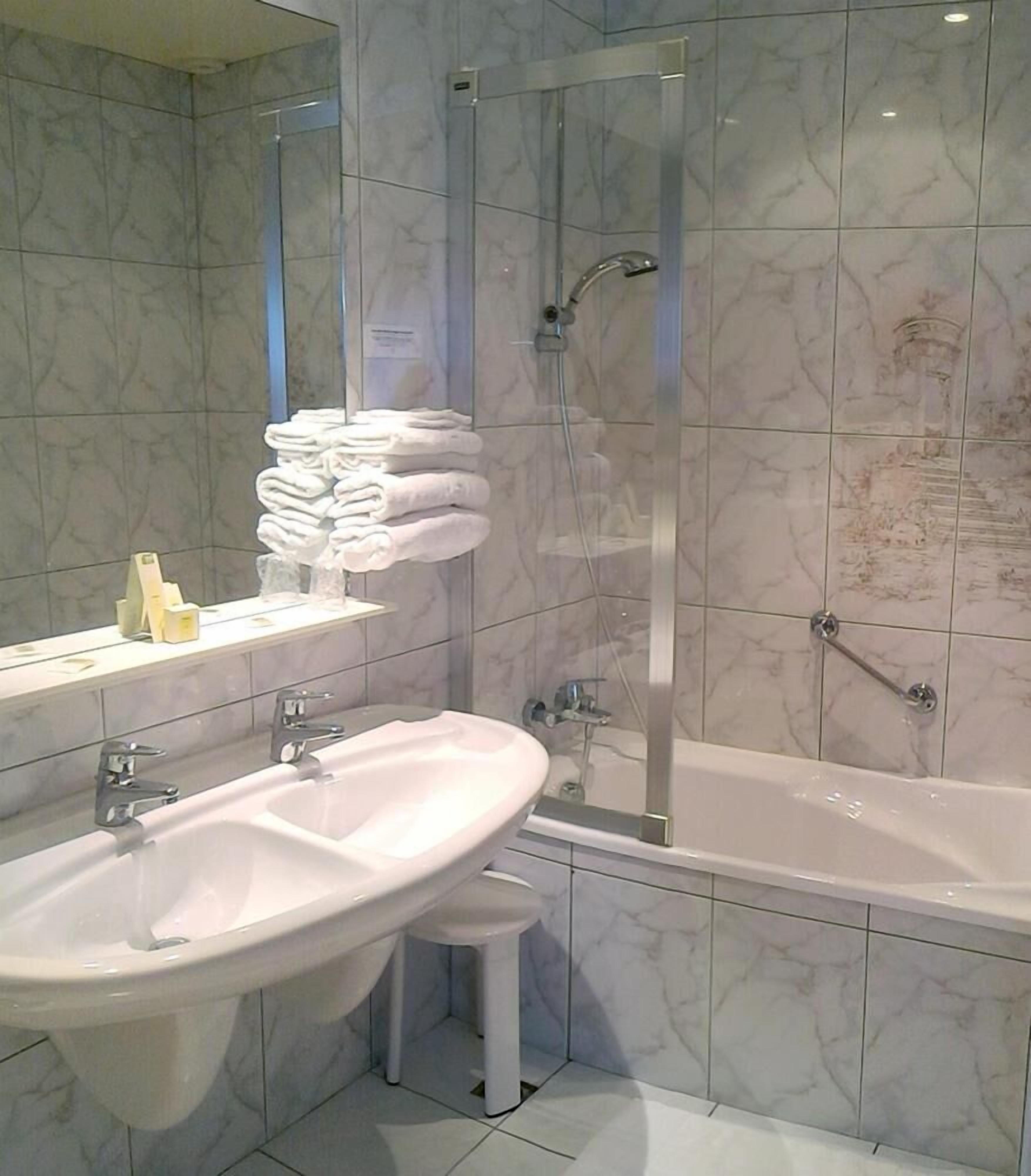 Un baño con lavamanos, espejo y zona de ducha con mampara de vidrio.