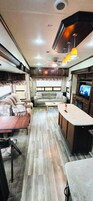 Interior compacto de una autocaravana con kitchenette, zona de estar y televisor.