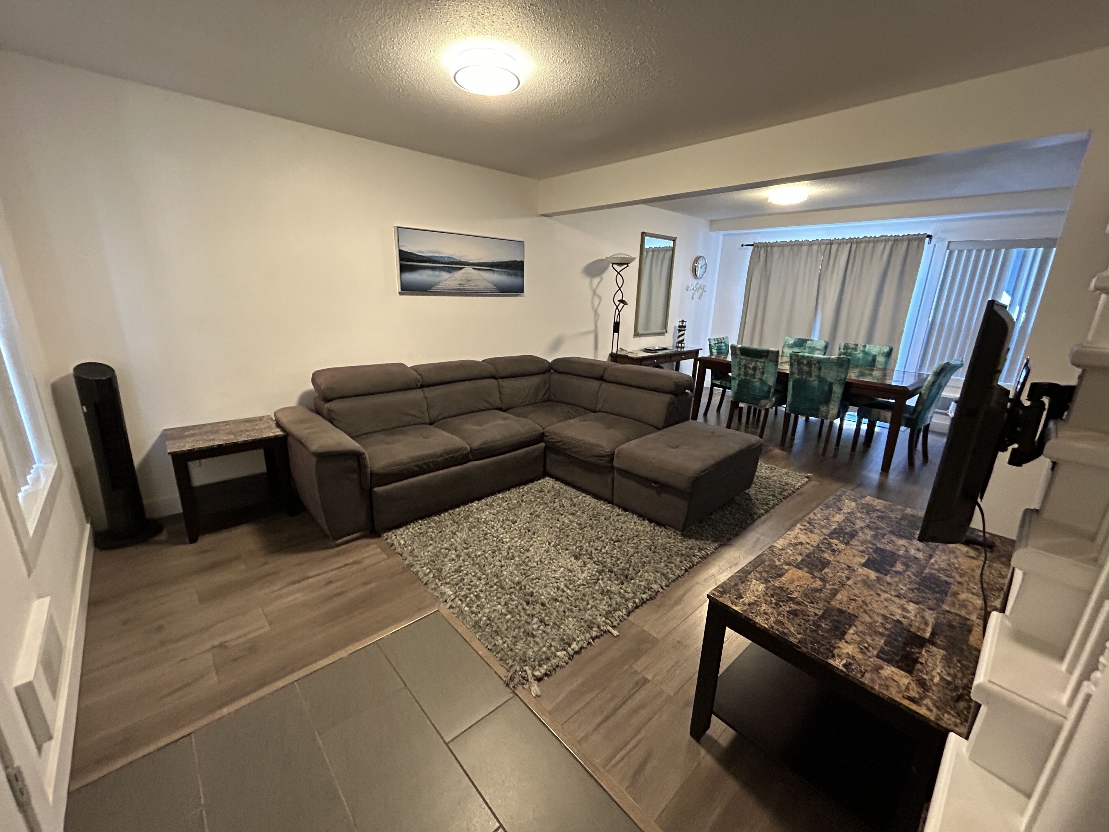 A living room with a sectional sofa, a coffee table, and a dining area with chairs and a table.