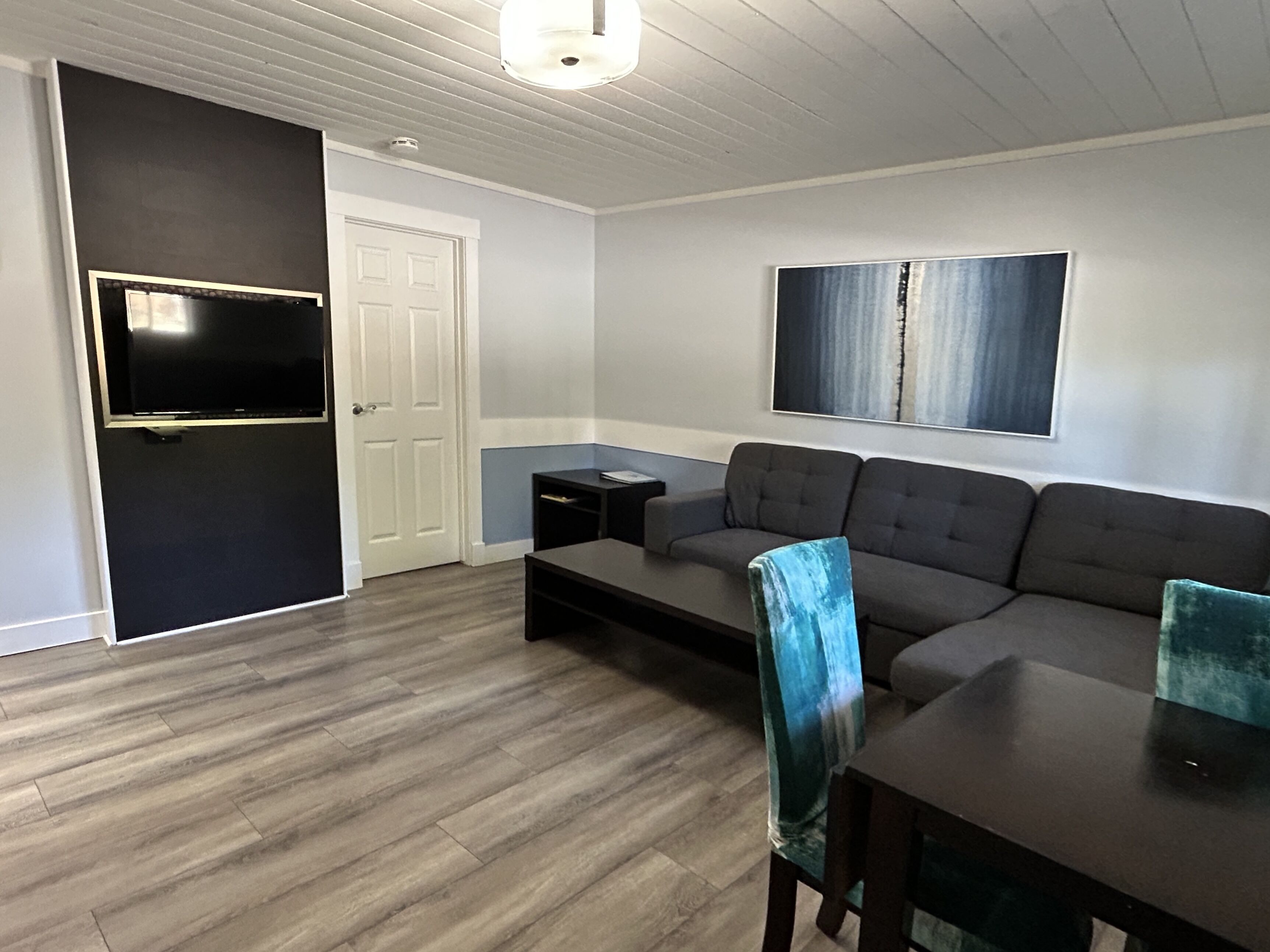 A modern living room with a grey sofa, a coffee table, and a TV mounted on the wall.