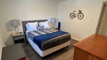 Een slaapkamer met een bed, nachtkastjes, een bureau en een aan de muur bevestigde fiets.