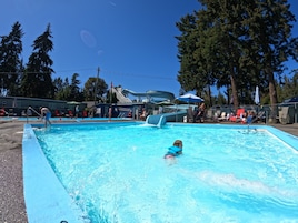 Una piscina con socorrista, sillas de descanso y un tobogán de agua.