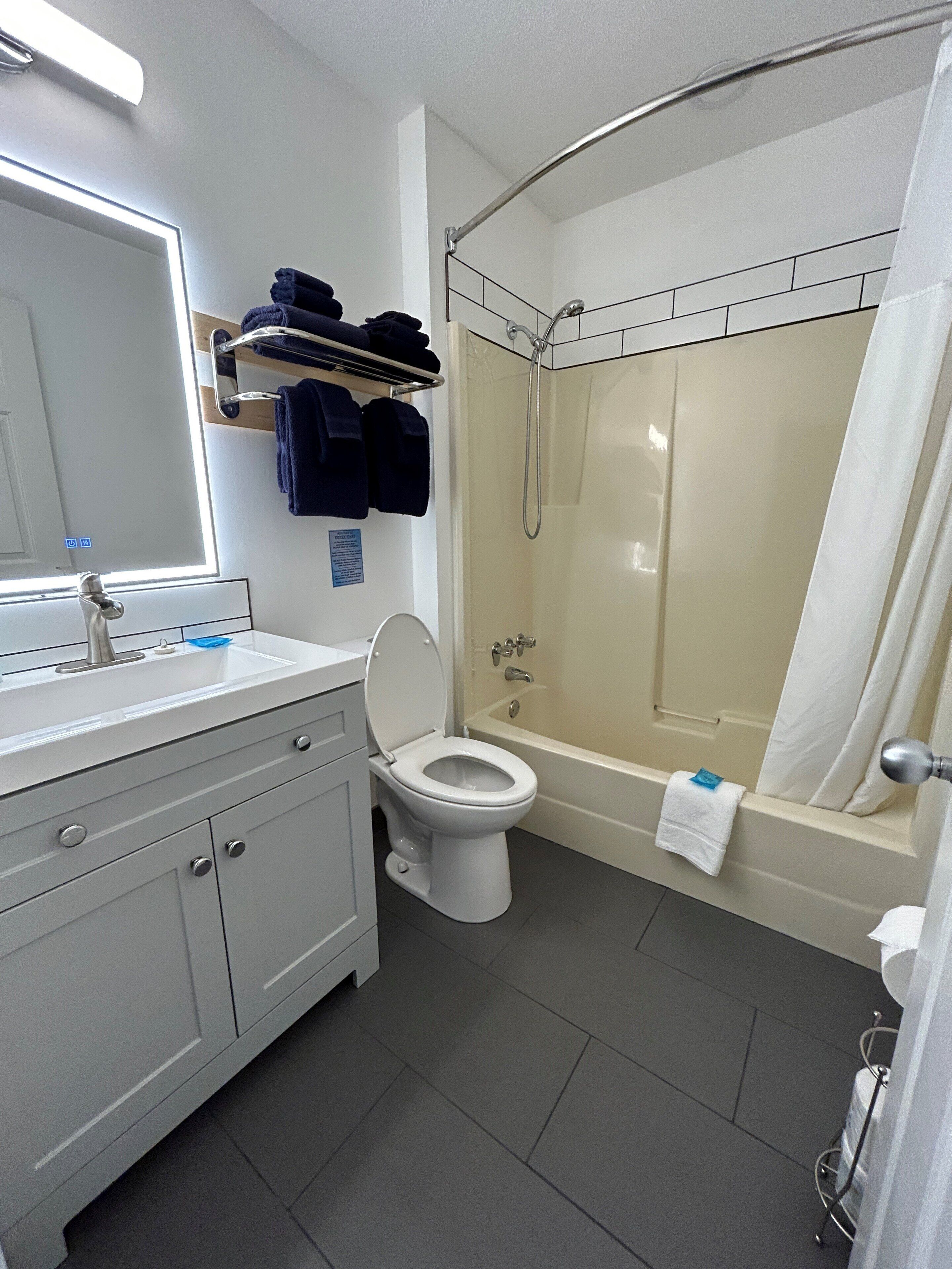 Une salle de bain moderne avec un lavabo blanc, des toilettes, une baignoire et une douche.