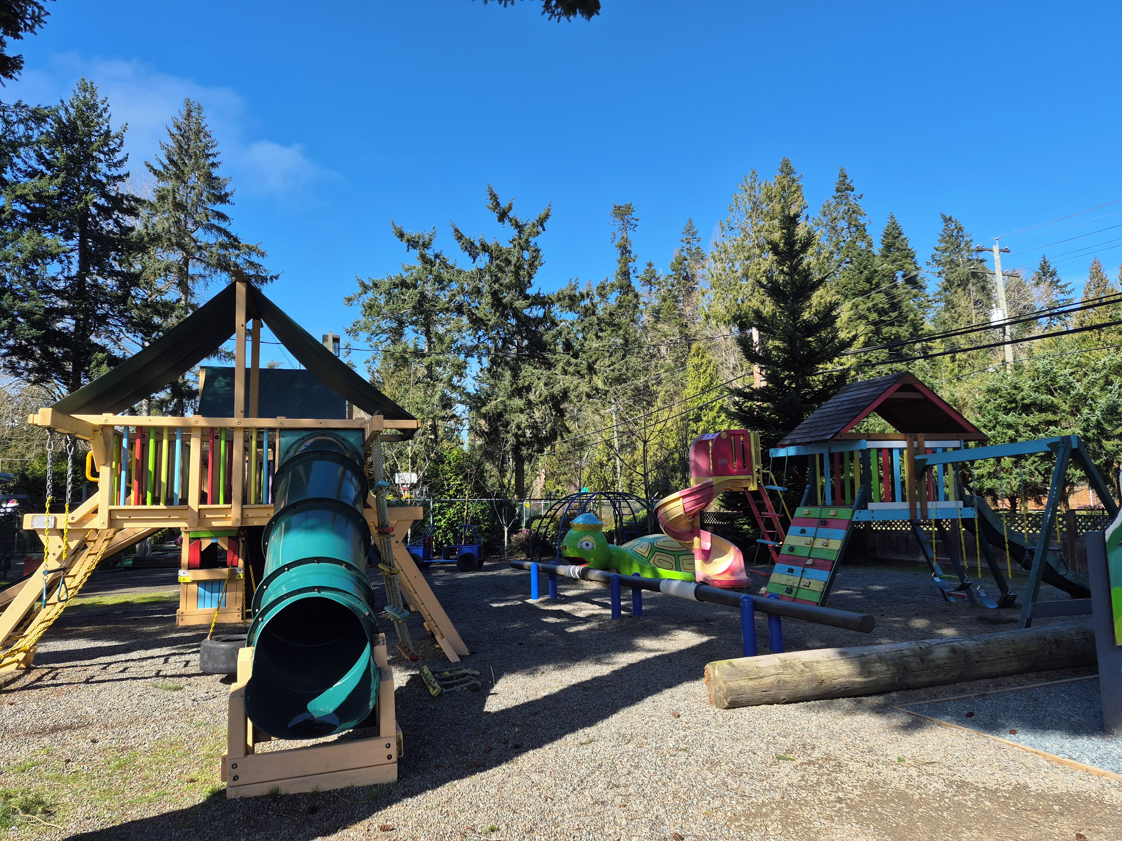 A playground with a slide, climbing structures, and a small building.