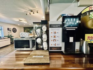 A coffee shop interior with a coffee machine, a hot beverage dispenser, and a sign detailing coffee service steps. - Riverside Resort & RV Park (Qualicum Beach)