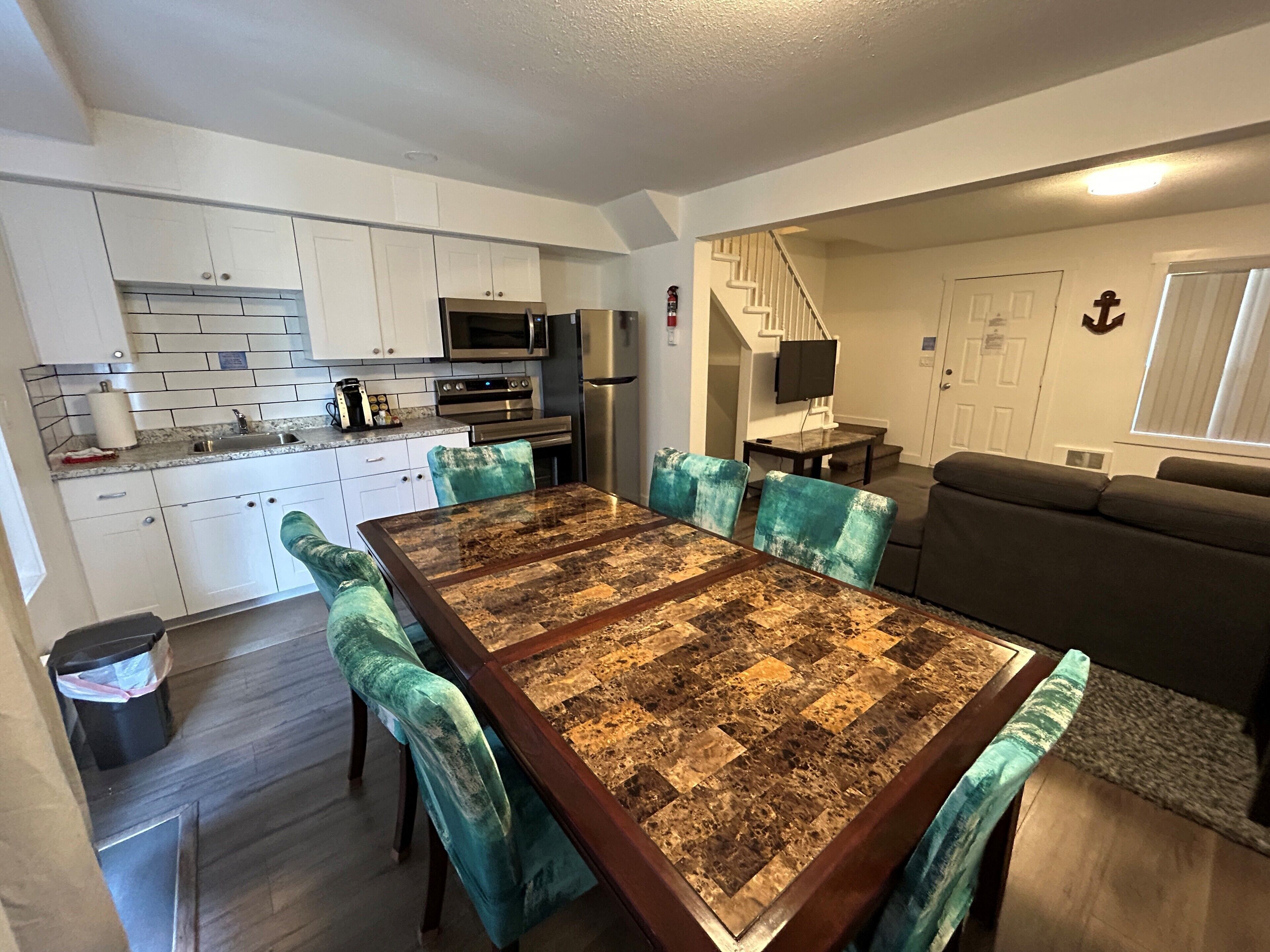 A modern kitchen with white cabinets, a stainless steel refrigerator, and a built-in oven.