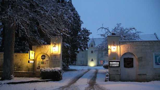 A snow-covered entrance to a building with illuminated signs and a welcoming archway. - Le Manoir de la Giraudière (Beaumont-en-Veron)