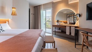 A modern hotel room with a large bed, a desk with a mirror, a bathroom with a sink, and a balcony with a view. - FERGUS Bermudas (Calvia)
