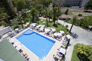 Una piscina al aire libre, sombrillas, sillones reclinables de piscina