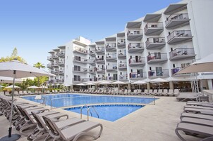 Una piscina al aire libre, sombrillas, sillones reclinables de piscina