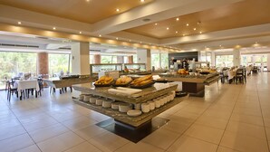 A spacious buffet area with multiple serving stations, tables, and chairs arranged for dining. - FERGUS Bermudas (Calvia)