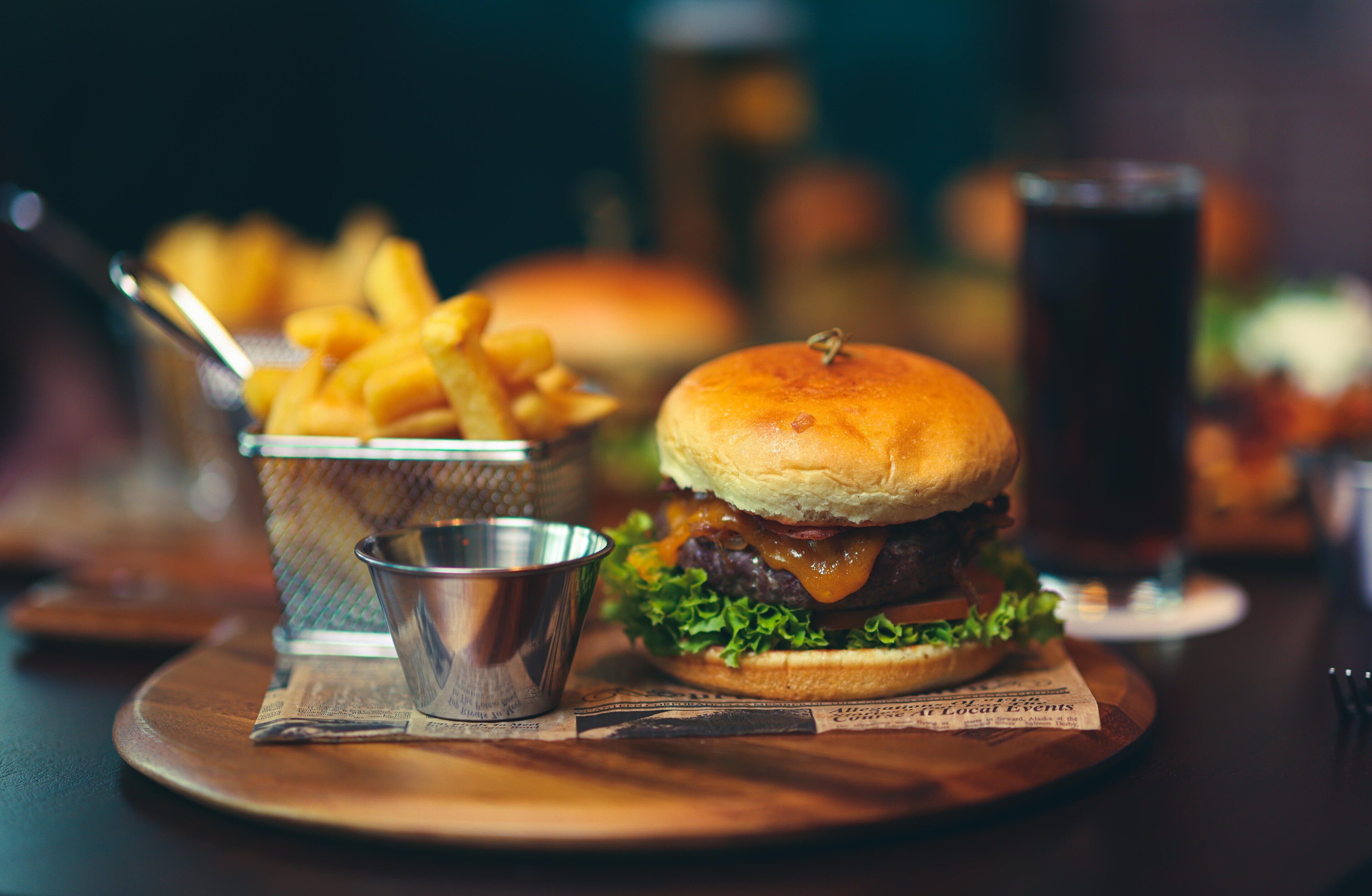 Una hamburguesa con papas fritas y una bebida sobre una mesa de madera.