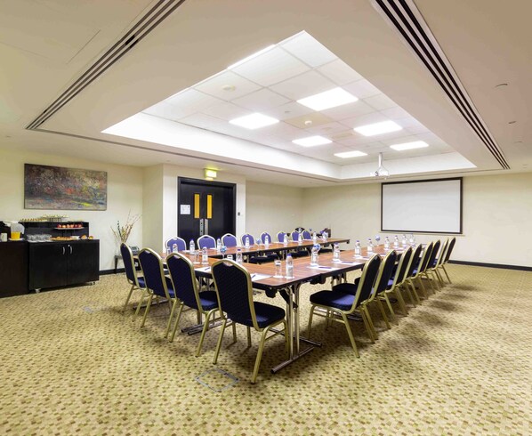 A conference room with a long table, chairs, a projector screen, and a buffet area. - Holiday Inn Express Dubai Airport by IHG (Dubai)