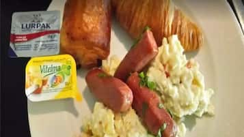Un plato con cruasanes, salchichas, huevos revueltos y un paquete de mantequilla Lurpak.