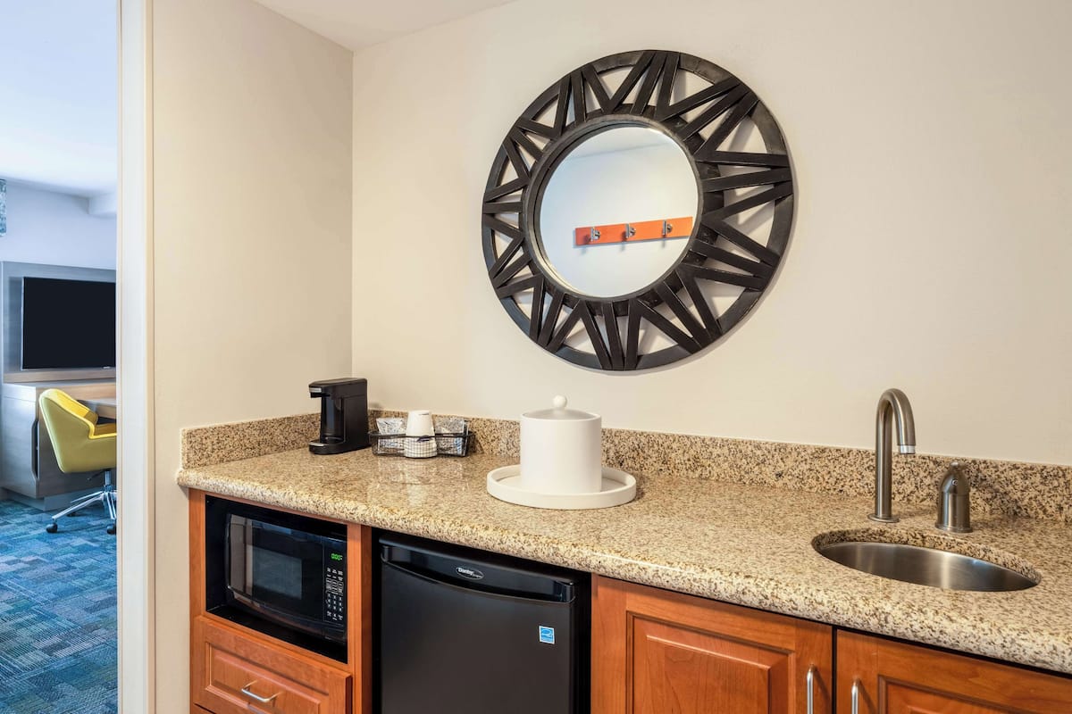 A compact kitchen with a granite countertop, stainless steel sink, and a built-in dishwasher.