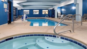 A swimming pool with a 3-step entry, lounge chairs, and a changing room in the background.
