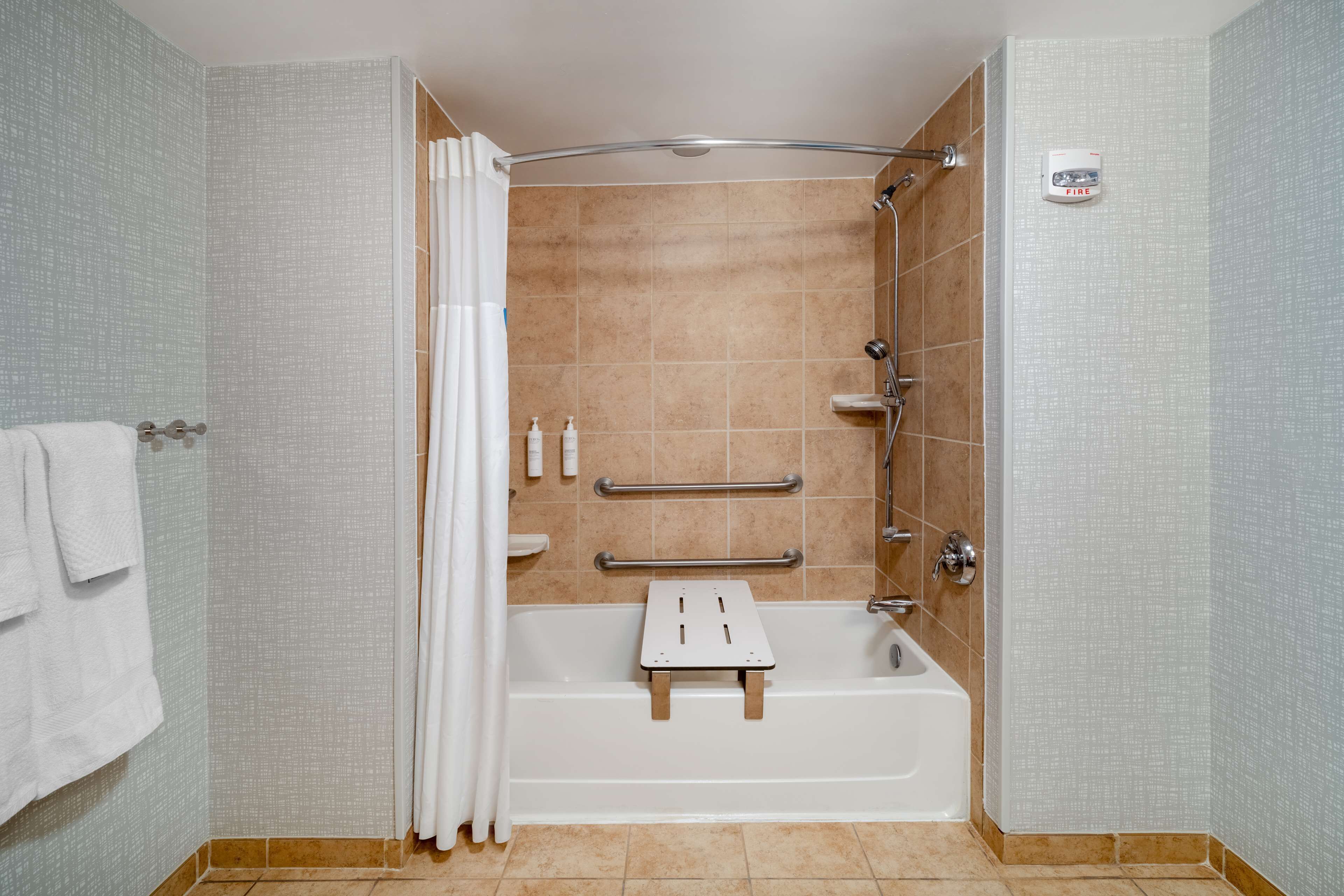 A modern bathroom with a bathtub, shower, and grab bars.