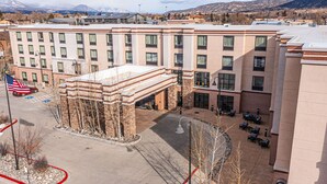 A multi-story hotel with a central courtyard, outdoor seating, and a view of mountains in the background.