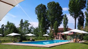 Una piscina al aire libre, sombrillas, sillones reclinables de piscina