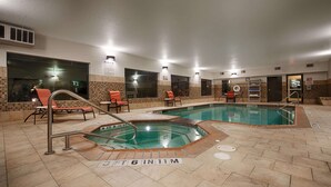 Una piscina interior con suelo de baldosas, sillas de descanso y un cartel que indica prohibido bucear.